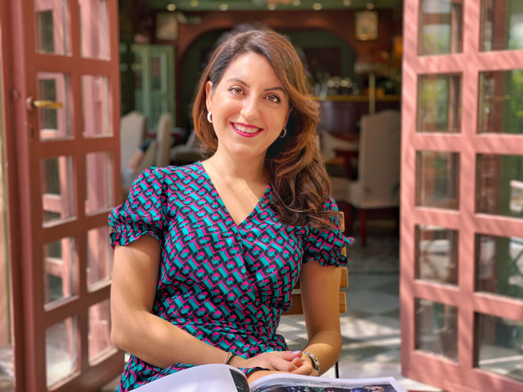 Nadin Rayya content designer sitting in a coffee shop reading a magazine and smiling